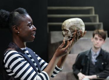 LAMDA student looking at a skull during 2019 MA Classical Actors' performance of Hamlet