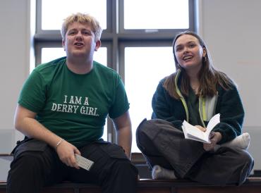 Students smiling and holding scripts in rehearsal